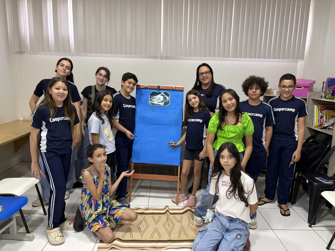 Turma do segundo encontro do clube do livro ao lado do mural azul