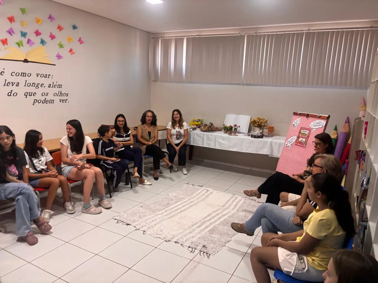 Roda de conversa do clube do livro em sala com estante e mesa de lanche